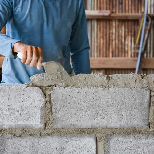 Bricklayer laying bricks on mortar
