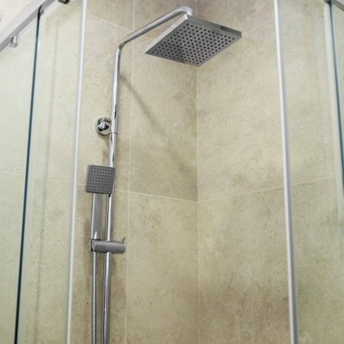 Close up shower in bathroom on beige tile wall backgrounds.