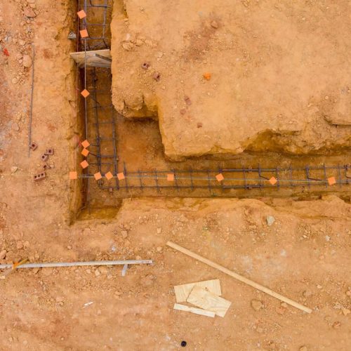 Performing works of putting steel in a trench for a house foundation on a construction site
