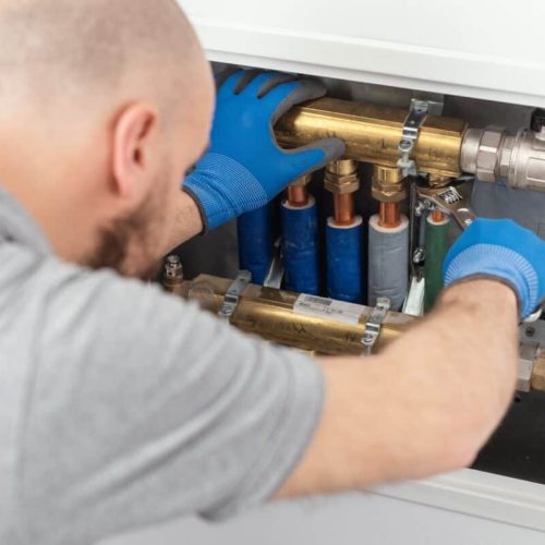 Professional plumber installing plumbing manifolds