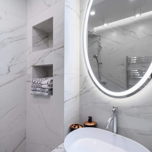 White bathroom interior with marble tiles on the walls