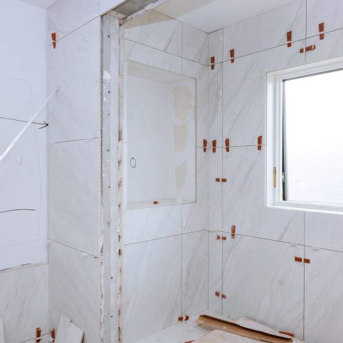 Work laying tile before applying tiles on bathroom tile.